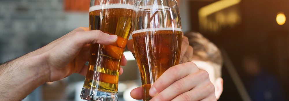 Male friends drinking beer and clinking glasses at bar